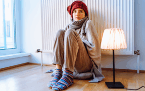 Woman in hat and scarf in front of radiator